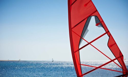 windsurfing-sail-close-up-against-blue-sea-and-sky-2023-11-27-05-37-18-utc-1